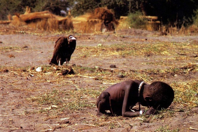 Abutre e a Garotinha (1993), do fotógrafo sul-africano Kevin Carter. A foto, publicada pelo The New York Times e vencedora do Pulitzer em 1994, mostra uma criança sudanesa faminta, caída no chão, enquanto um abutre espera pacientemente por sua morte. Carter esperou cerca de 20 minutos para fazer a imagem e, depois, espantou a ave. A criança sobreviveu ao episódio, mas a imagem perseguiu o fotógrafo: criticado por não ter ajudado, Carter suicidou-se poucos meses após receber o prêmio. No Sudão as crianças comem biscoito de terra. Penso ser uma imagem radicalmente incoerênte. Humanos não comem terra. Nosso estômago não evoluiu com tal capacidade.